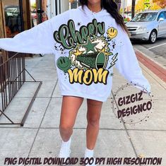 a woman is walking down the street wearing a white sweatshirt dress with green mom on it