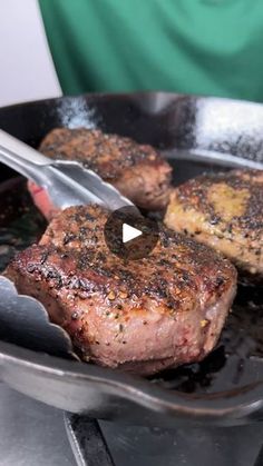 two steaks being cooked in a skillet with a spatula on the side