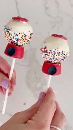 someone holding two cake pops with sprinkles on them