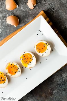 three hard boiled eggs on a white plate with black pepper sprinkles next to them