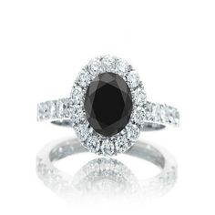 a black and white diamond ring with diamonds around it's center stone, set in 18k white gold