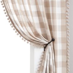 an open window with a checkered curtain and pom - poms