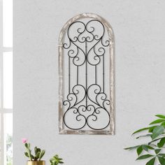 an iron window on the wall above a potted plant