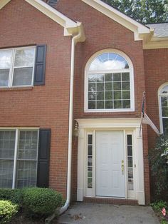 a brick house with white doors and black shutters