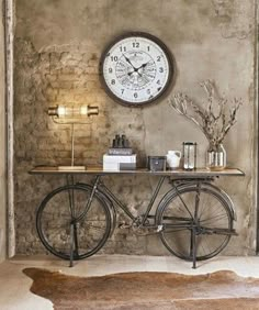 a bicycle is parked in front of a clock on the wall above it, next to a shelf with books and other items