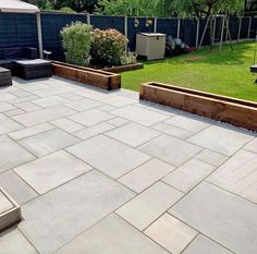 an outdoor patio with raised planters and seating area in the back yard, surrounded by grass