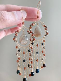 Indulge in luxury with these exquisite multi-gemstone waterfall chandelier earrings.  Featuring natural sapphire, pyrite, sandstone, black opal and black spinel.  These long, elegant earrings are the perfect gift for her. Ideal for anniversaries, and special occasions, they make a standout statement for mom, wife, girlfriend, sister, daughter, or aunt.  All components including ear wires are gold filled and handcrafted by me. They are easy to wear and comfortable even for a sensitive skin. Material Sapphire  Pyrite  Sandstone  Black opal  Black spinel  Gold filled wire Gold filled ear wires  Length : 4 inches  WANT MORE?  ENTER MY SHOP https://www.etsy.com/shop/SweetStoneLove  SHIPPING  The processing time for most orders is 1-2 business days.    Enjoy free US standard shipping on orders o Bohemian Gemstone Dangle Chandelier Earrings, Bohemian Gemstone Chandelier Dangle Earrings, Unique Dangle Earrings With Gemstone Beads, Artisan Dangle Chandelier Earrings, Cluster Jewelry, Waterfall Chandelier, Sundance Jewelry, Long Chandelier, Handmade Wire Jewelry