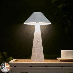 a lamp that is sitting on top of a table next to a cup and saucer