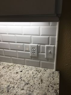 the light is on in this kitchen with granite counter tops and white tile backsplash