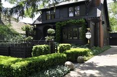 a black house with hedges in front of it