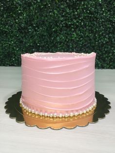 a pink frosted cake sitting on top of a black and gold plated platter