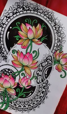 a drawing of pink flowers on white paper with black and gold accents, sitting on a red cloth