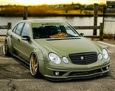 a green car parked in a parking lot next to a body of water at sunset