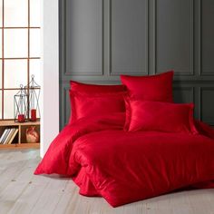 a bed with red sheets and pillows in a room