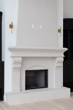 a white fireplace in a living room with black furniture