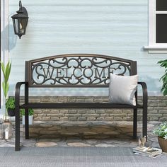 a metal bench sitting in front of a brick wall next to a potted plant