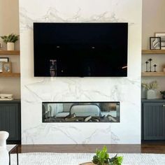 a large flat screen tv mounted on the wall above a fireplace in a living room