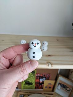 there is a small snowman on top of the other tiny snowmen in front of a shelf