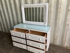 a white wicker dresser with two drawers and a mirror