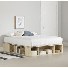 a bed with storage drawers underneath it in a white room next to a door and rug