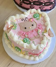 two cakes decorated with pink and white frosting on top of a wooden table next to each other