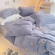 an unmade bed with blue sheets and yellow stars on it, next to a pair of gray slippers