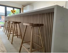 a row of wooden stools sitting in front of a counter with sunflowers on it