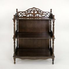 an antique wooden shelf with carvings on the top and bottom, against a white background