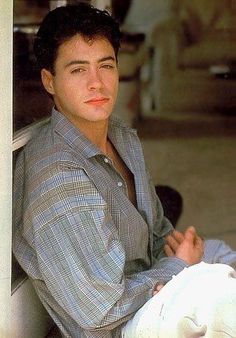 a young man is sitting on the porch with his arms crossed and looking at the camera