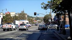 several cars are stopped at an intersection in the city with traffic lights and signs above them