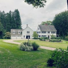 a large white house sitting in the middle of a lush green field next to trees