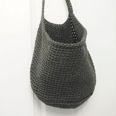 a crocheted bag hanging on the wall next to a white door with a black handle