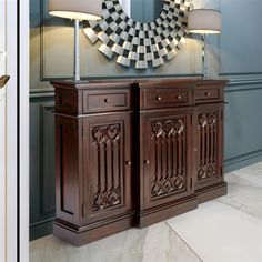 a wooden cabinet with two lamps and a mirror on the wall in front of it