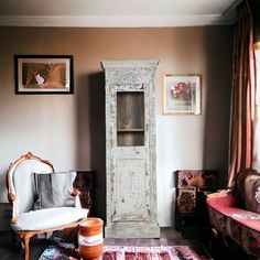 a living room filled with furniture next to a tall cabinet in the middle of it