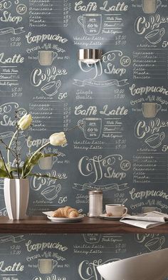 a table with some flowers in a vase on it next to a chalkboard wall