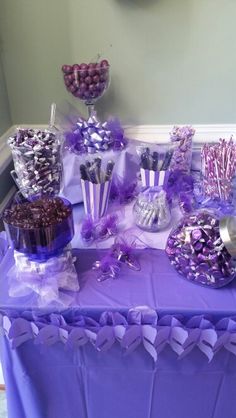 a purple table topped with lots of candies and lollipops on top of it