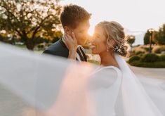 a bride and groom kissing in front of the sun shining through the veil on their wedding day