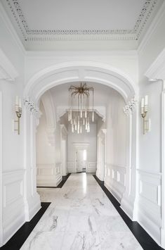 an empty hallway with chandeliers and marble flooring on either side of the hall