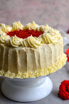 a cake with white frosting and red sprinkles on top sitting on a table