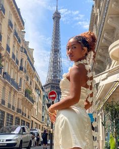 a woman is standing in front of the eiffel tower wearing a white dress