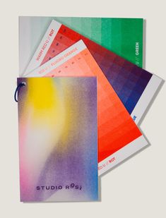 three notebooks with different colored papers on them