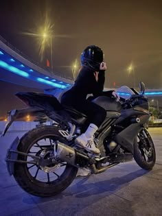 a person sitting on top of a motorcycle in front of a stadium at night time