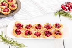 small cranberry tarts on a white plate with rosemary sprigs next to them