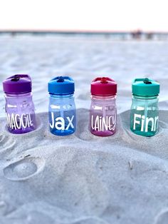 three jars with names on them sitting in the sand