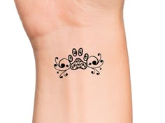 a black and white tattoo design on the side of a woman's wrist,