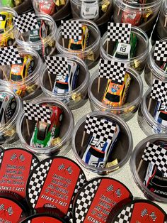 many plastic cups with race cars in them on a counter top next to other cupcakes