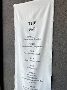 a white towel hanging on the side of a wall next to a black and white sign