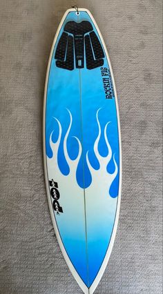 a surfboard with flames painted on it laying on the floor next to a wall