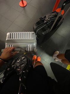 a person is sitting on the floor with their feet propped up next to an open suitcase