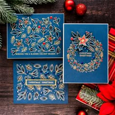 two cards with christmas designs on them next to some presents and decorations, one is blue